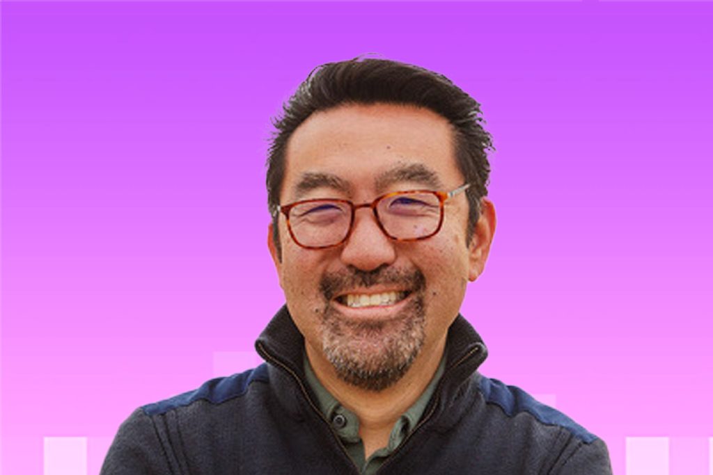 Headshot of Gene Kim: Asian man in 50s with a goatee smiling wearing glasses