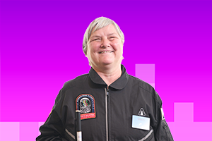 Sheri smiling with short hair wearing her Astro Access space suite and holding her cane