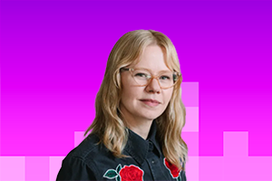 Lauren - white woman with shoulder length blonde hair wearing glasses and a denim shirt with two red roses