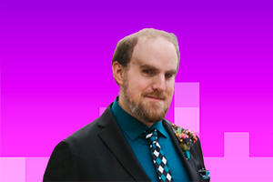 Marco - white man with a beard and short hair wearing a black suit with a teal shirt and tie