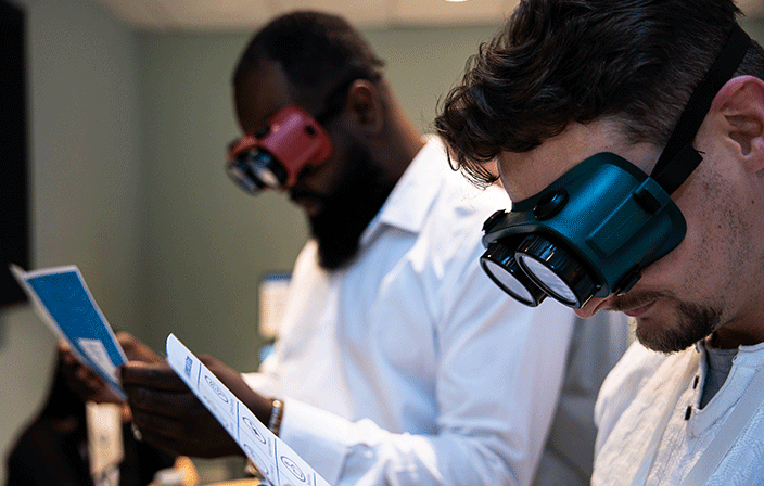 Two awareness lab participants reading while wearing vision typr goggles.