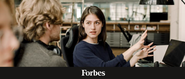 A woman gesturing at a computer behind the Forbes logo