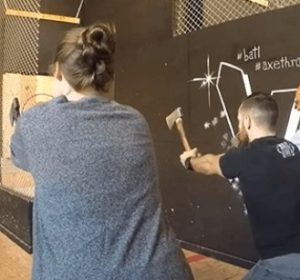 A Deque employee getting axe throwing lessons