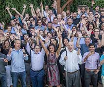 Deque employees smiling with their hands raised in the air at a big group event outdoors