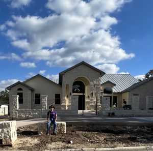 Patrick in front of his newly built home sitting on a block of solid limestone called a butter stick in the front yard. The home is mostly complete but there is still some landscaping work in the front yard to be completed.