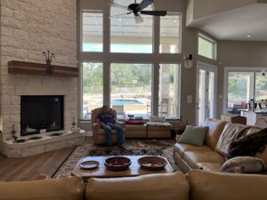 Patrick sitting in a comfy chair in his living room next to the fireplace. The room is fully built, furnished, and decorated.