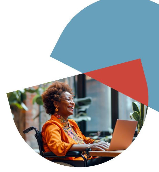 woman in wheelchair sitting at desk and smiling at laptop screen