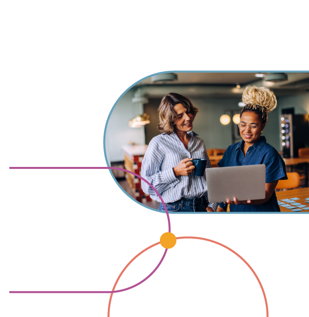 Two colleagues huddled over a laptop and smiling