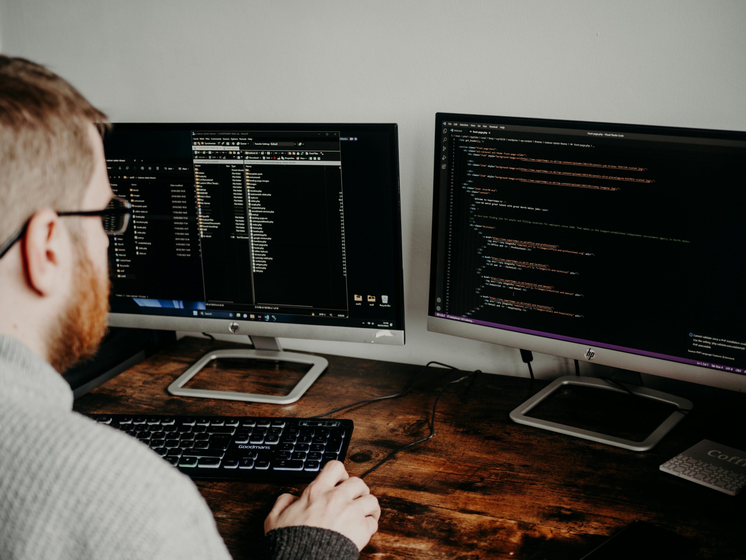 Man coding at desk with two monitors